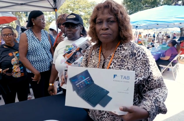 A community member showing a Figgers tablet at an outdoor event.