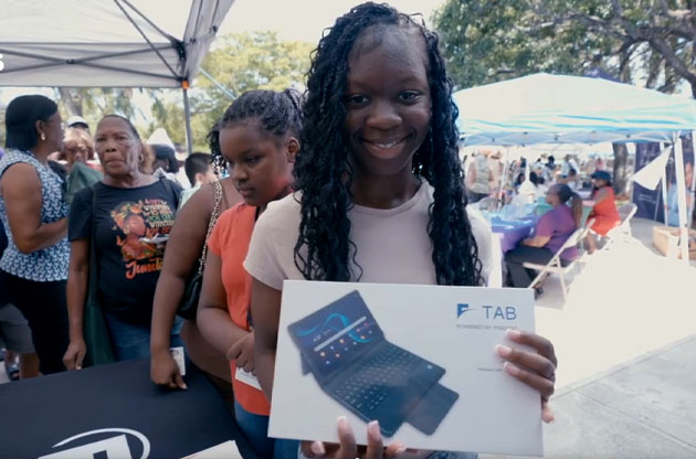 A young woman receiving a Florida Connect tablet at a community event.
